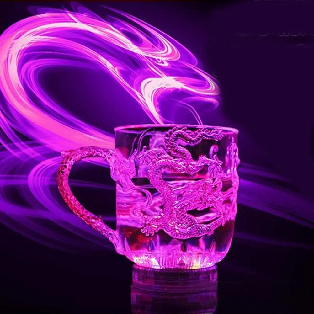 A clear mug featuring an etched dragon design glows with vibrant pink and purple light, surrounded by swirling colored smoke.