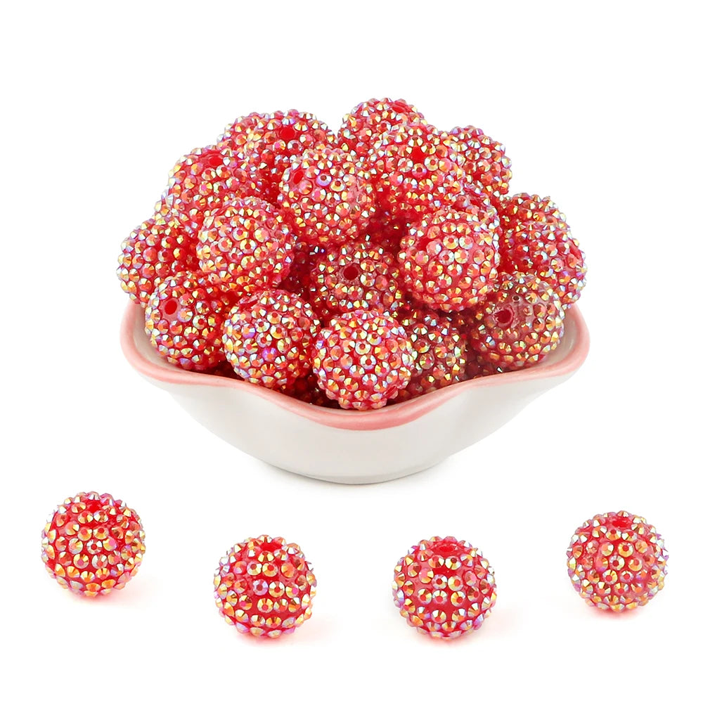 A pile of bright red and pink rhinestone resin bayberry beads for jewelry making.