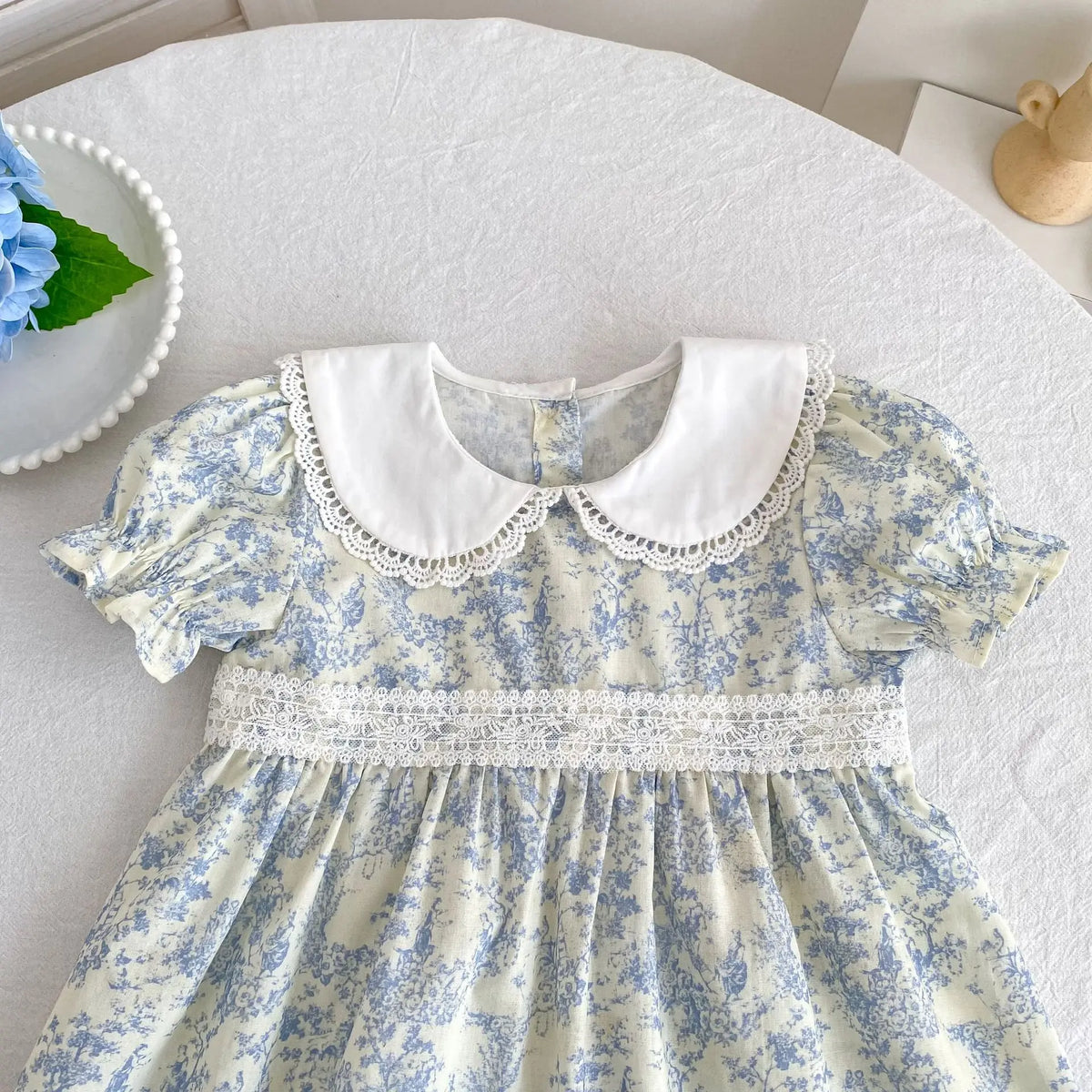 A light blue and white floral dress for girls featuring a white Peter Pan collar and delicate lace trim.