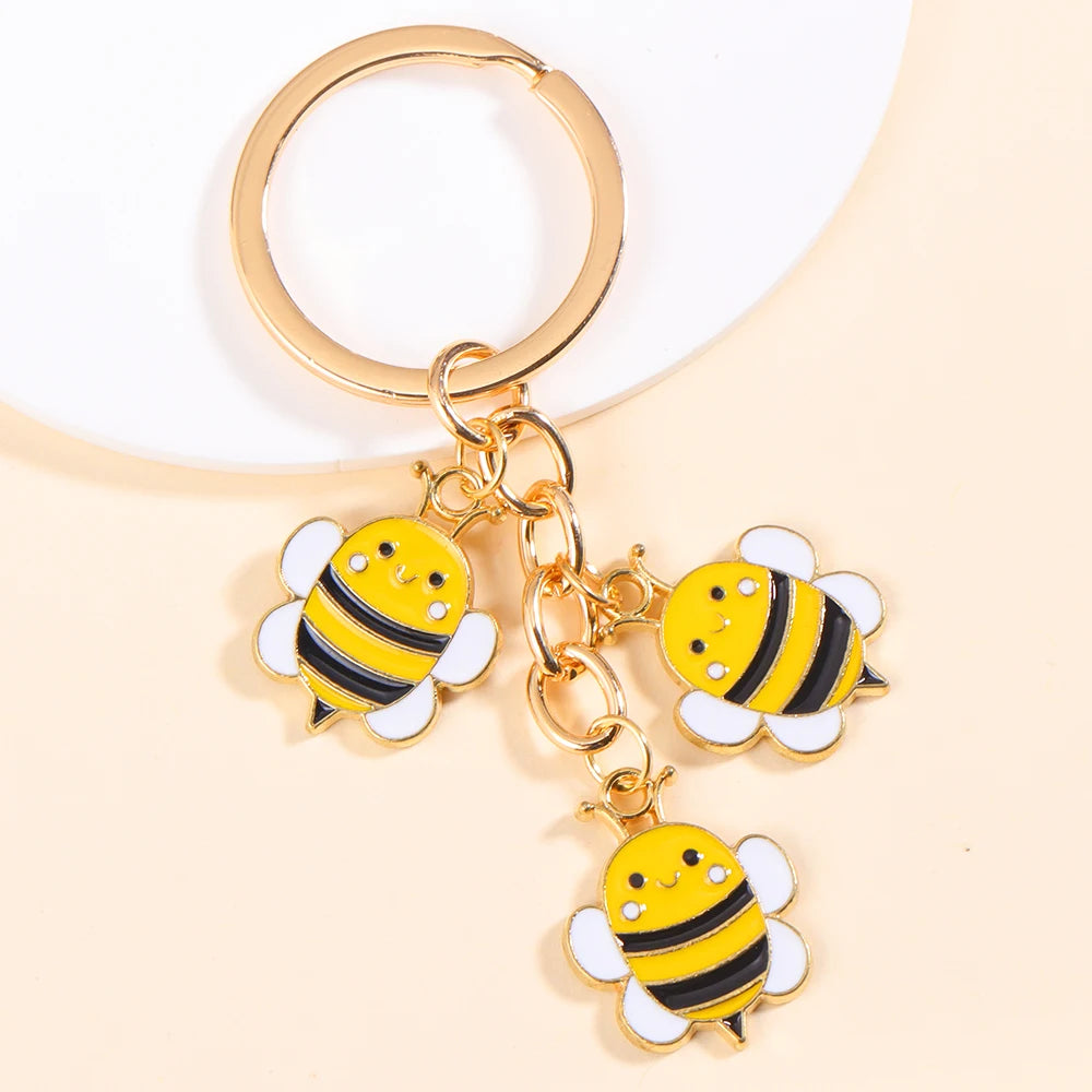 Gold-toned keychain featuring enamel bees and a daisy design.