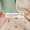 Close-up of soft, textured cotton fabric in sage green and blush pink tones.
