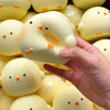 A hand is holding a white squishy toy shaped like a chick, surrounded by other similar toys.