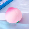 Rosa Pfirsich-Squishy Stressabbau-Spielzeug auf einer hellblauen Oberfläche.