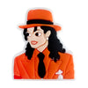 A silicone charm depicting a woman with long dark hair wearing an orange jacket and hat.