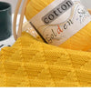 A ball of bright yellow cotton knitting yarn next to a finished knitted garment.