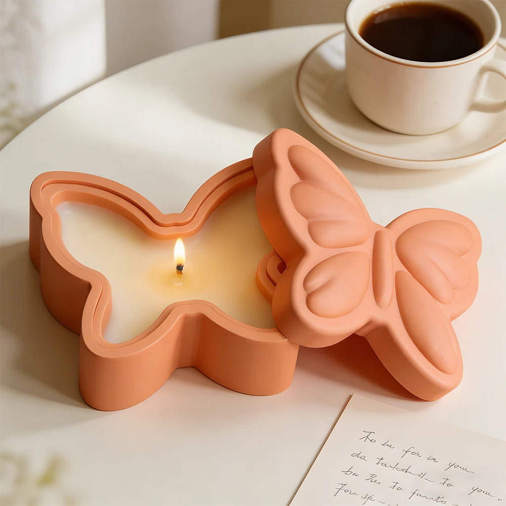 A terracotta silicone resin mold shaped like a butterfly with a lid, resting on a white surface.