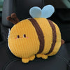 A yellow and brown plush pillow shaped like a bee with blue wings, resting on a black seat.