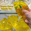 A hand holds a yellow honey cheese squishy toy, showing its texture and slow-rise quality.