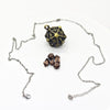 A metal polyhedral dice set with a pendant storage case displayed on a white background.