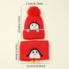 A red knit penguin hat with a fluffy pompom and a matching red knitted scarf.