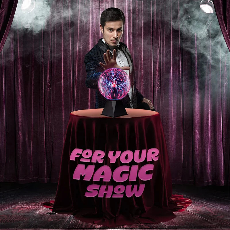 A magician in a suit is performing with a glowing purple plasma ball on a draped table.