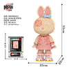 A fully assembled bear figure made of pink and beige micro building blocks with a blue bow.