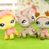 A set of three pastel-colored LPS-style vinyl cat figurines with scarf necklace accessories sitting on green grass.