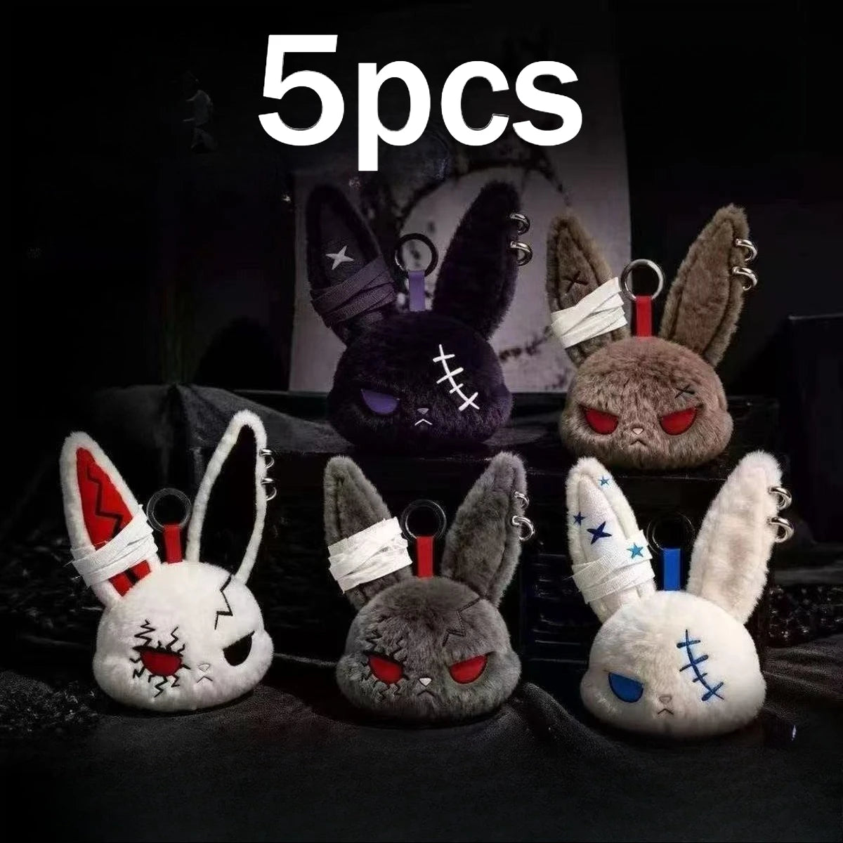 Five gothic bunny plush keychains with bandages and ears displayed on a dark surface.