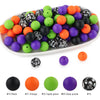A variety of colorful silicone beads in black, orange, green, and purple are displayed in a white dish.