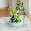 A clear glass jar filled with green and pink flower building blocks on a white surface.