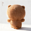 A fluffy brown panda plush toy viewed from the back, with a small pin visible on its head.