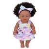 A 12-inch realistic African American baby doll with a purple and white floral dress and a bow in her hair.