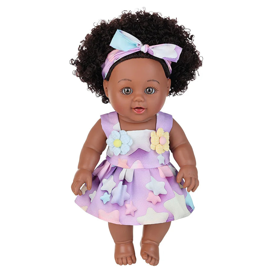 A 12-inch realistic African American baby doll with a purple and white floral dress and a bow in her hair.