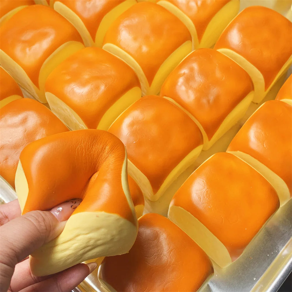 Une main tient un pain décoratif en forme de boule orange avec une doublure jaune.