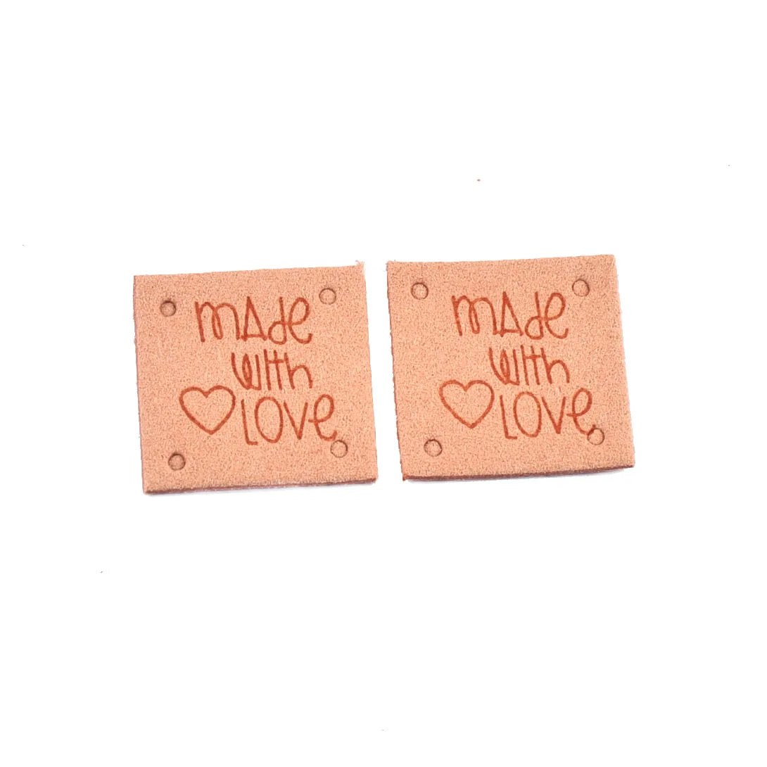 Two pink embossed leather labels with the text Made with Love stamped on them