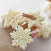 White snowflake silicone mold for candle soap and wax melts displayed on a wooden surface.