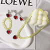 A set of princess jewelry accessories featuring a yellow beaded necklace and earrings with red stones, displayed on a white s