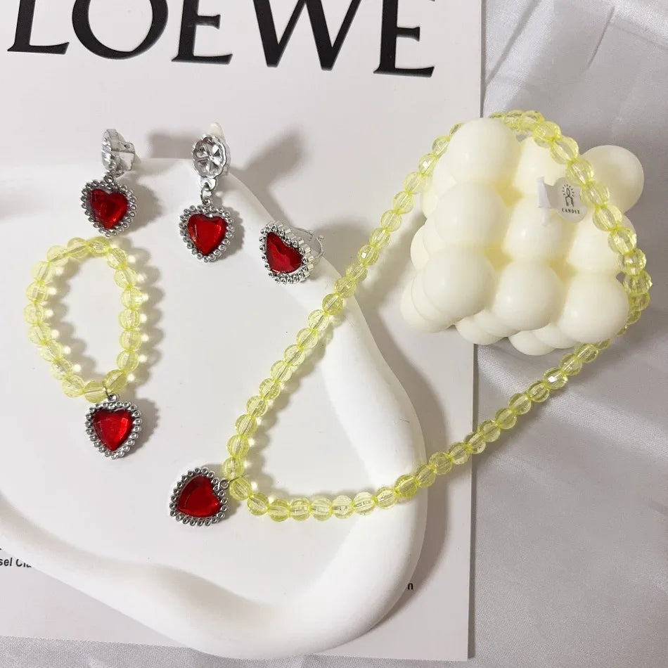 A set of princess jewelry accessories featuring a yellow beaded necklace and earrings with red stones, displayed on a white s