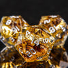 A close-up of a set of golden resin dice with elven numbers, reflecting light on a dark surface.