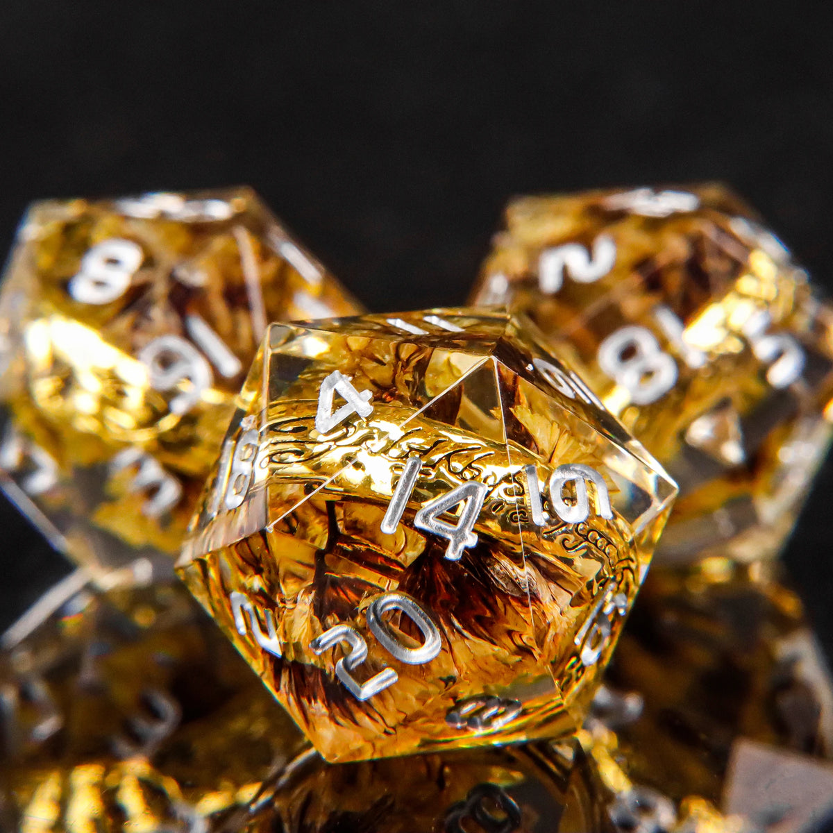 A close-up of a set of golden resin dice with elven numbers, reflecting light on a dark surface.