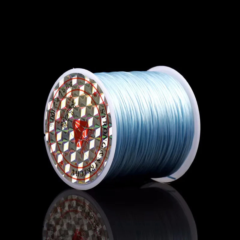 A spool of blue elastic beading cord for stretch bracelets and necklaces is shown against a black background.