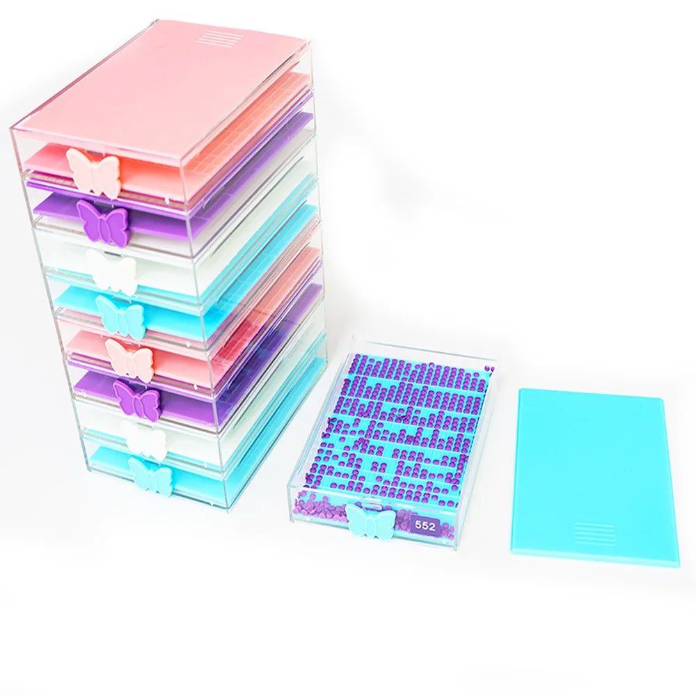 A stack of clear acrylic diamond painting storage trays with pink, purple, and blue butterfly-shaped lids.