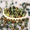A pile of vibrant round beads in shades of green and gold for jewelry making