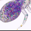 A purple, glittery, laser-reflective flexible fishing lure resembling a spider is shown.