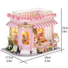Pink miniature dollhouse kit featuring a storefront with flowers and warm lighting.