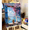 A painting of a pink cherry blossom tree and landscape in blue and white on a wooden frame.