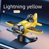 A lightning yellow solar powered rotating airplane dashboard ornament resting on a dark surface.