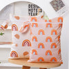 A set of two reusable waterproof baby wet bags featuring a pastel pink background with colorful rainbow patterns.