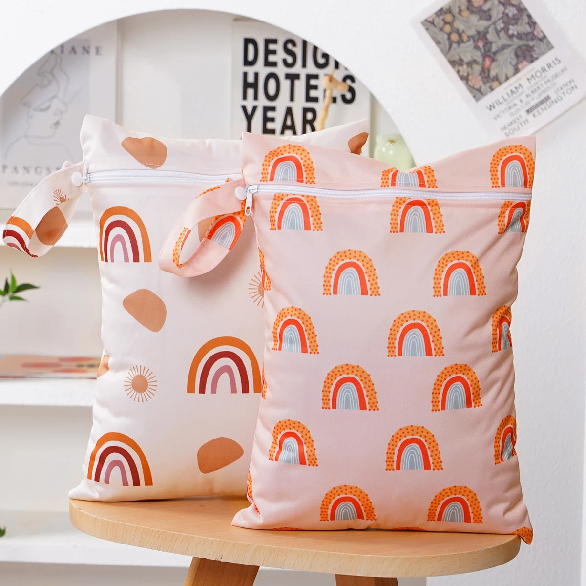 A set of two reusable waterproof baby wet bags featuring a pastel pink background with colorful rainbow patterns.