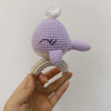 A handmade wooden baby rattle and teether ring shaped like an otter, featuring purple and beige yarn.