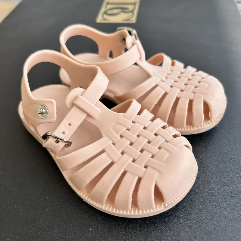 Pair of pink girls' gladiator jelly sandals with woven straps and non-slip soles