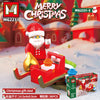 A red Santa figure is riding a red sleigh built from Christmas gift sled blocks in a snowy scene.