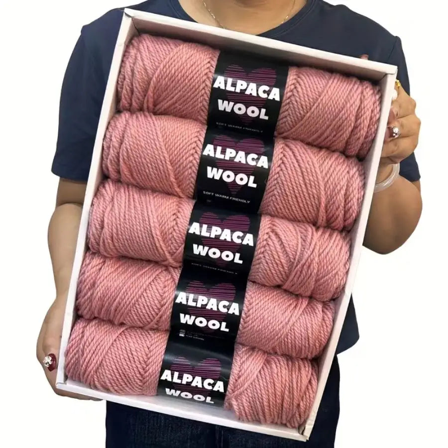 A box containing five skeins of pink alpaca wool yarn for knitting and crochet projects.