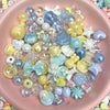A collection of iridescent acrylic bow and flower beads in various pastel colors like blue, yellow, and pink.