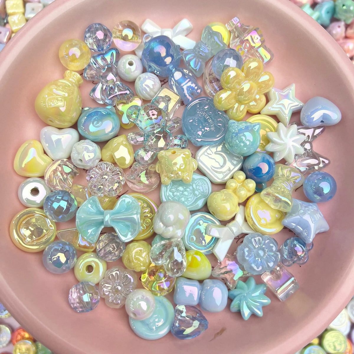 A collection of iridescent acrylic bow and flower beads in various pastel colors like blue, yellow, and pink.