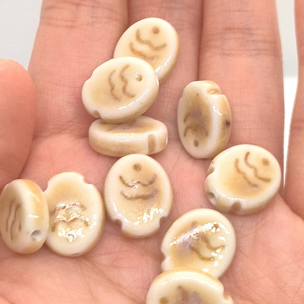 Several light beige ceramic fish charms are displayed on a hand, showing various shapes and textures.