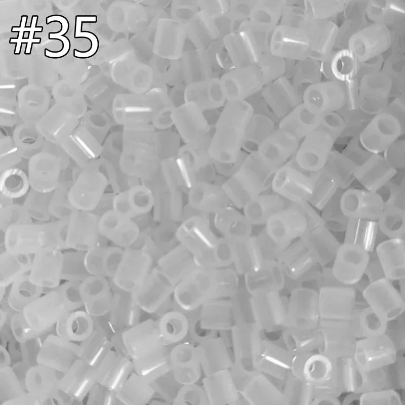 A close-up view of many small, clear plastic fuse beads in assorted colors and shapes.