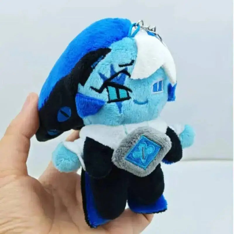 A soft blue and black plush collectible doll with white accents and a diamond pendant being held in a hand.