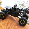 A black high-speed 4WD off-road RC truck with large tires and LED lights resting on an orange surface.