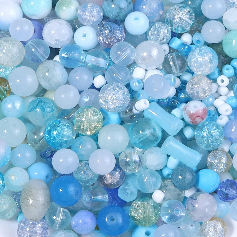 A close-up view of a vibrant mix of light blue, aqua, and purple glass beads for DIY jewelry making